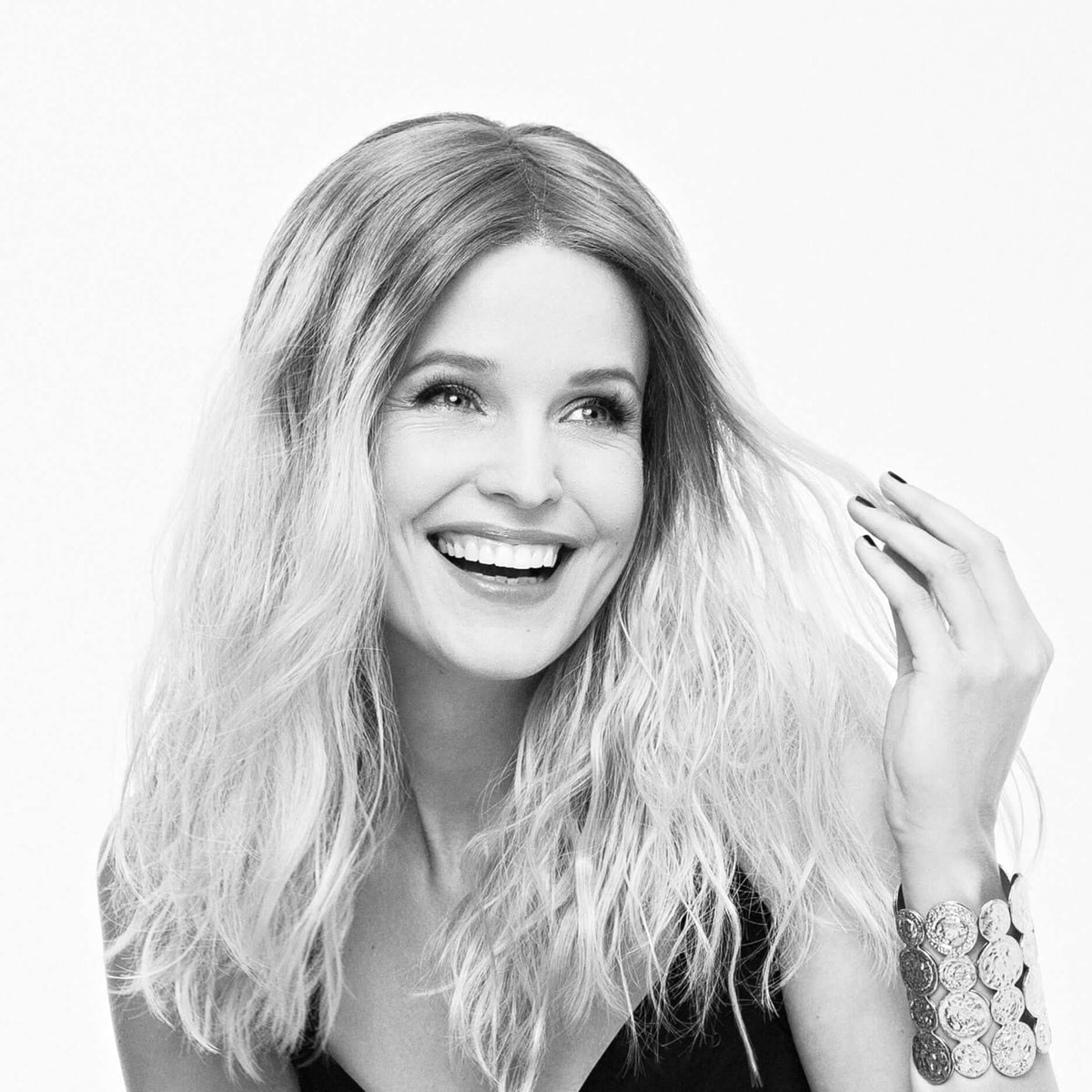 Smiling woman with long wavy hair, showcasing a joyful moment and elegant style.